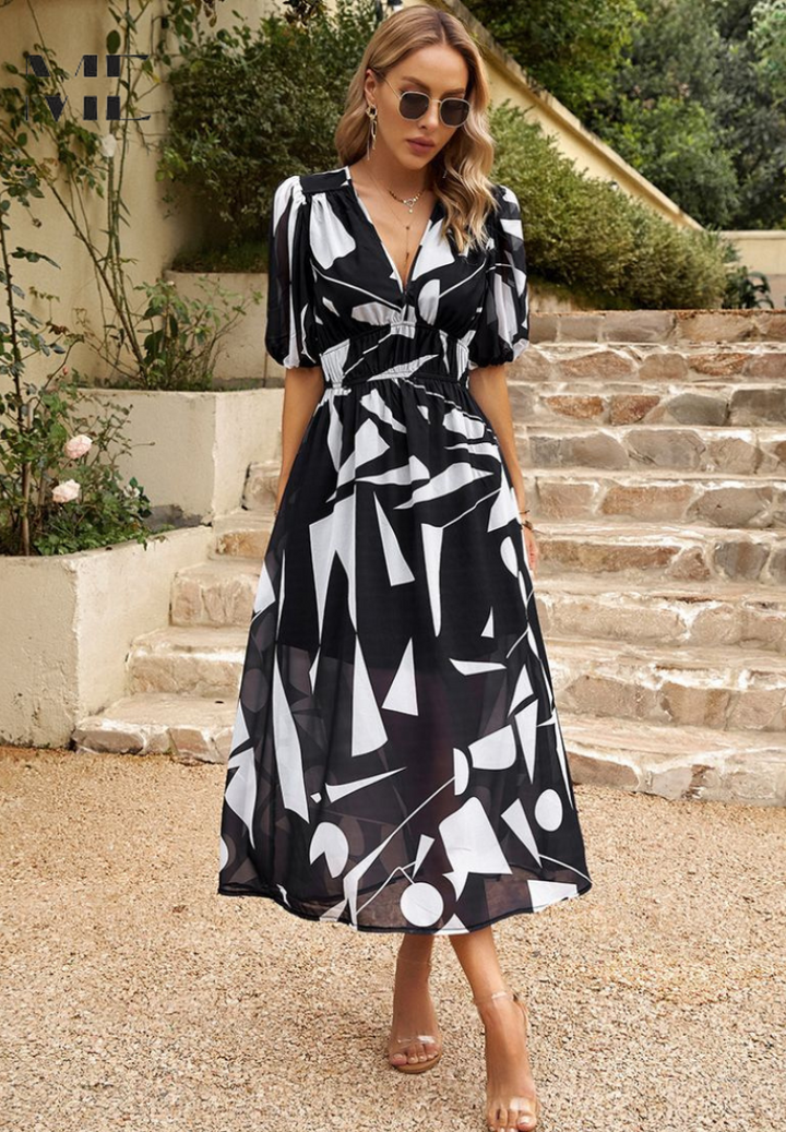Woman wearing a black and white geometric print midi dress with a V-neckline, gathered waist, and puff sleeves.