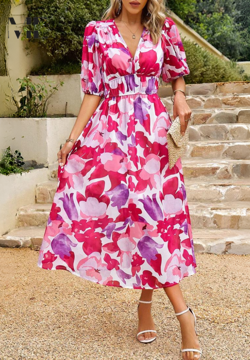 Woman wearing a pink and purple floral midi dress with a V-neckline, gathered waist, and short puff sleeves.