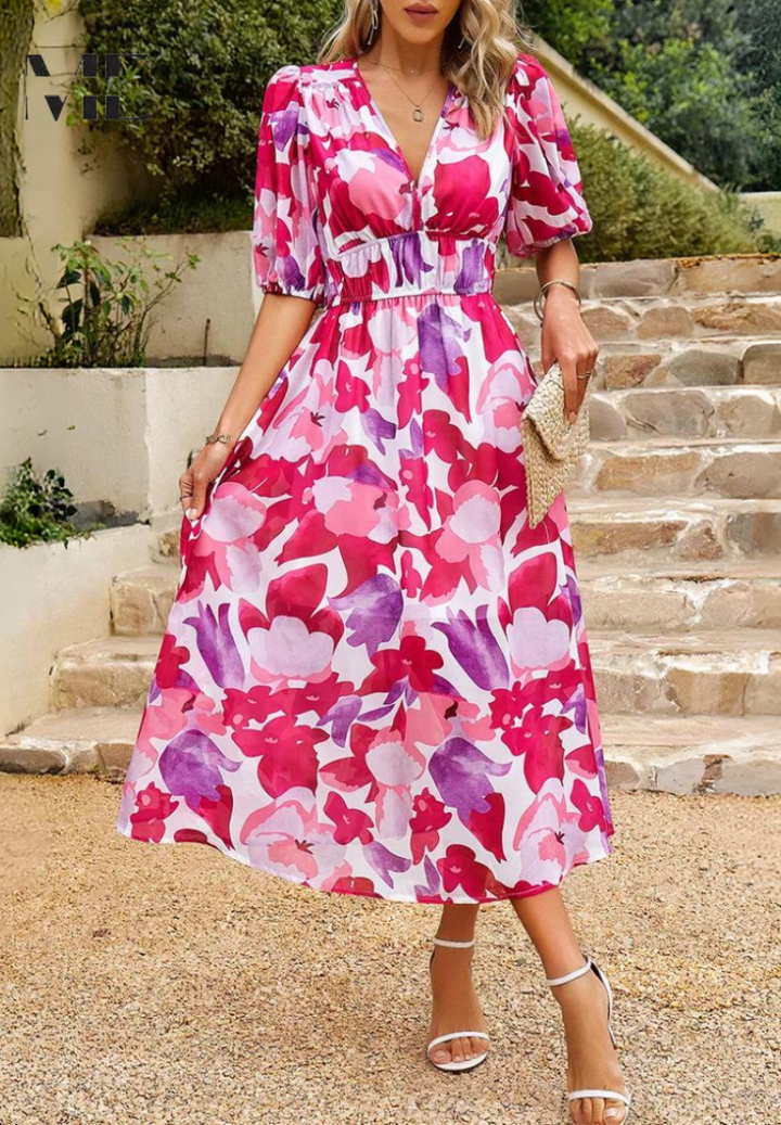Woman wearing a pink and purple floral midi dress with a V-neckline, gathered waist, and short puff sleeves.