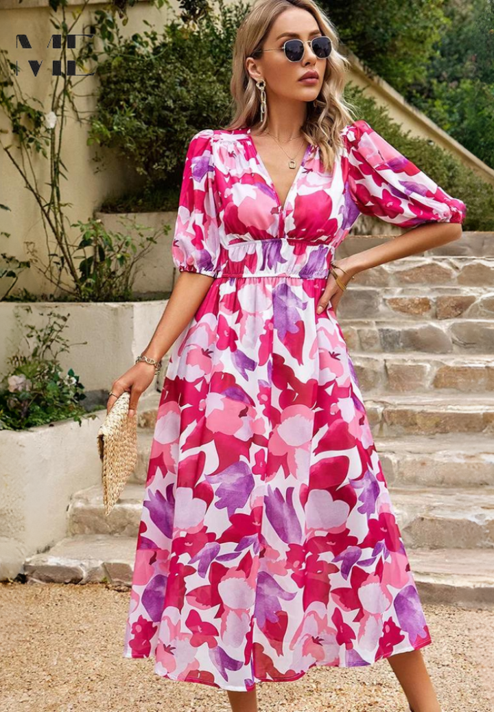 Woman wearing a pink and purple floral midi dress with a V-neckline and puff sleeves, standing on stone steps.