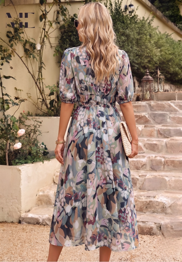 Woman wearing a floral midi dress with puff sleeves, a gathered waist, and a flowing skirt in a garden setting.