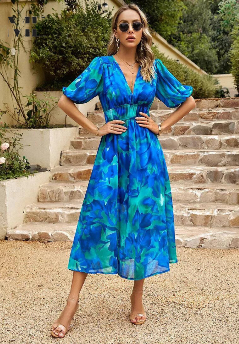 Woman wearing a blue and teal floral midi dress with a V-neckline, gathered waist, and romantic puff sleeves.