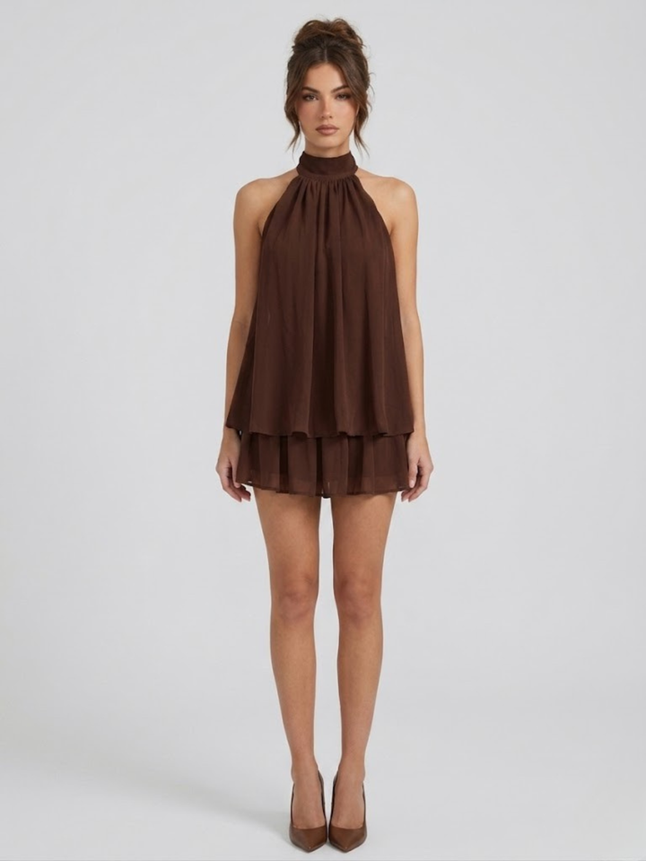 Brown halter neck mini dress with a tiered ruffle hem and lightweight, flowy fabric on a model.