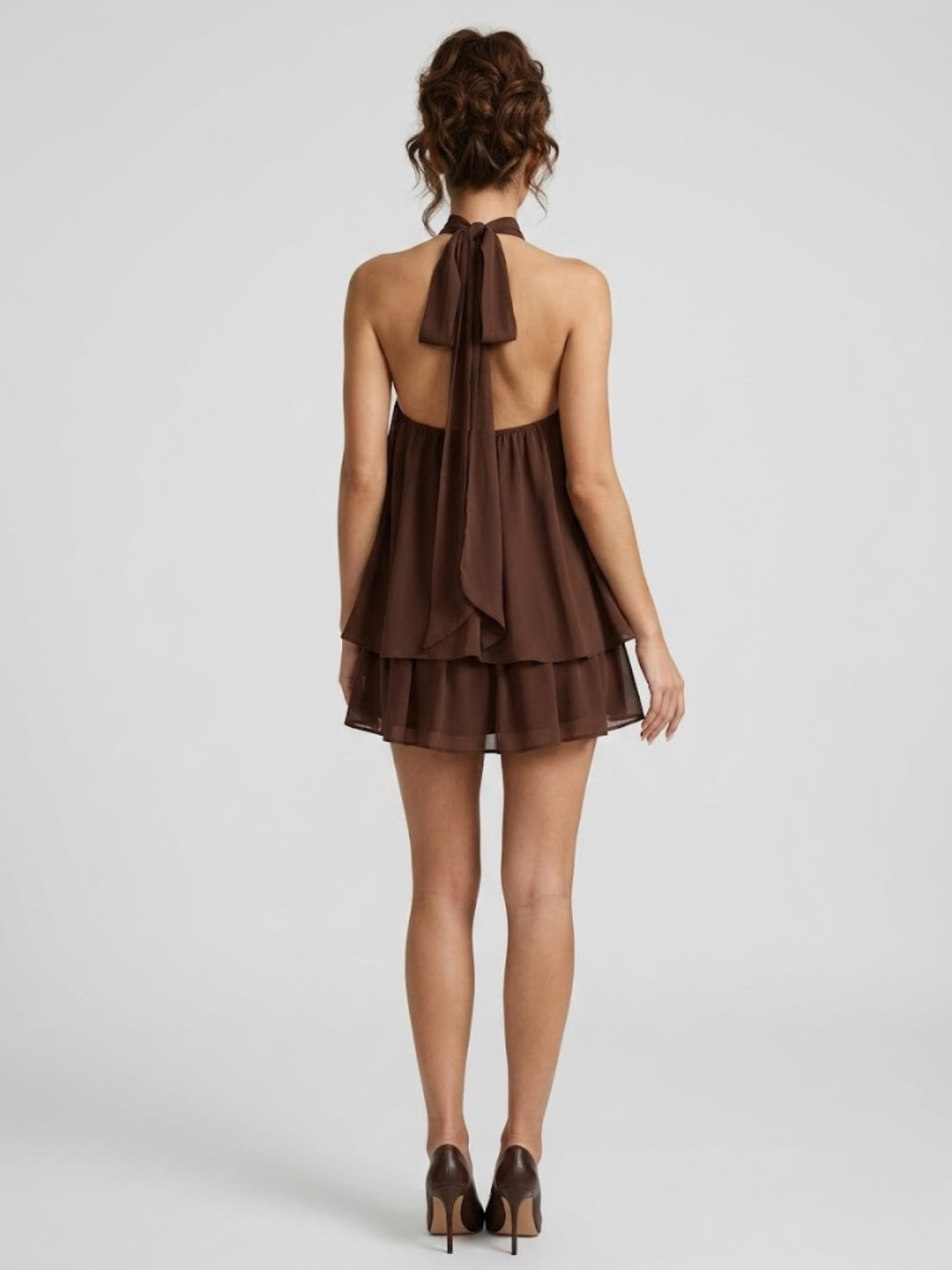 Back view of a brown halter-neck mini dress with an open back, self-tie straps, and a tiered ruffle hem.