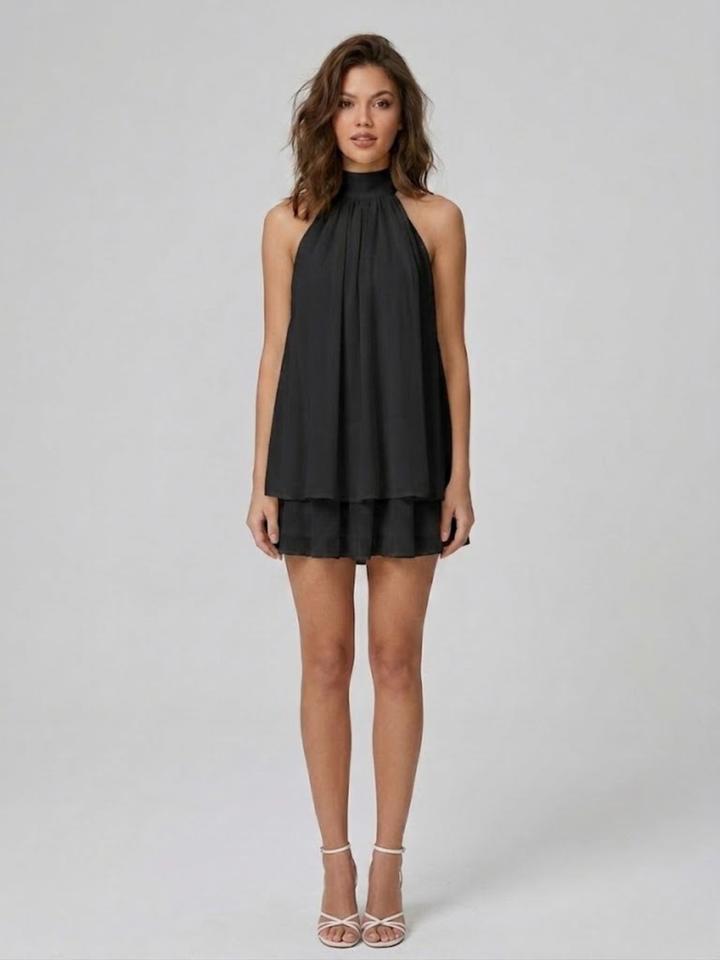 Black halter neck mini dress with a tiered ruffle hem and relaxed swing silhouette worn by a woman.
