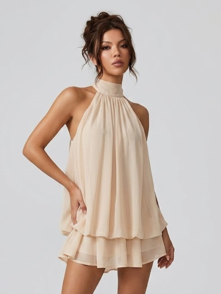 Beige halter neck mini dress with a tiered ruffle hem and flowy, lightweight fabric.