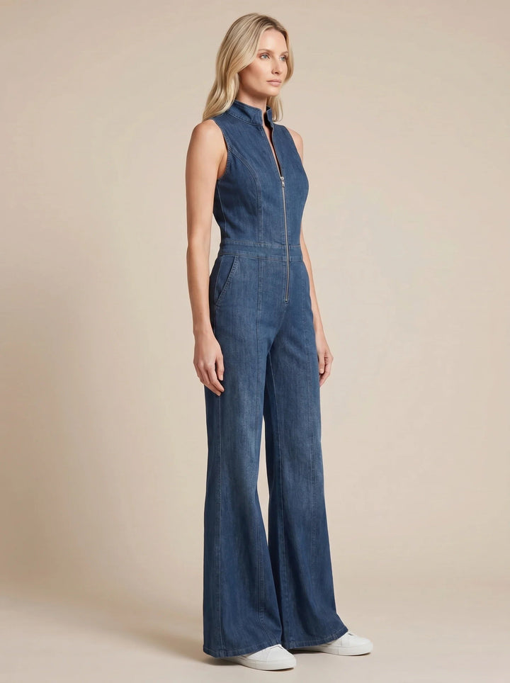 Sleeveless blue denim jumpsuit with a zip-front, stand collar, and wide flared legs on a model.