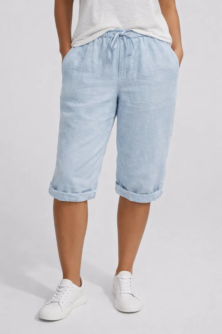 Light blue linen knee-length shorts with an elastic drawstring waist, side pockets, and rolled-up hems.
