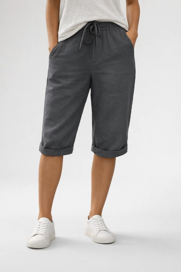 Charcoal grey linen knee-length shorts featuring an elastic drawstring waist, side pockets, and rolled-up hems.