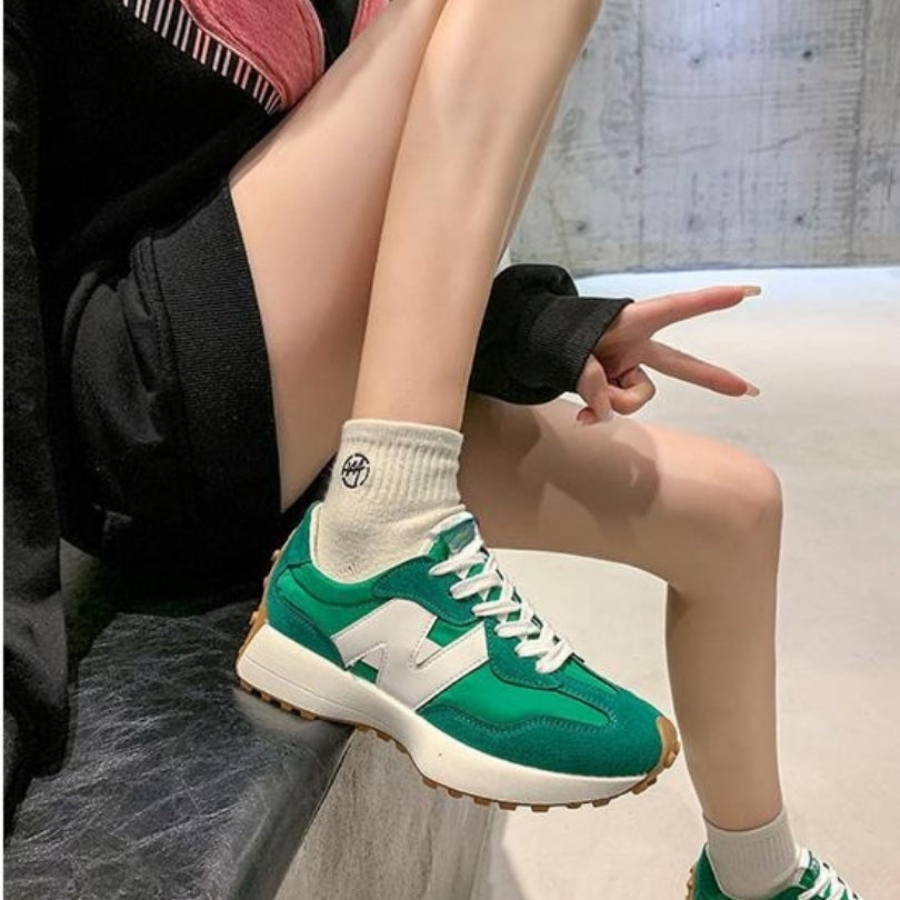 Green and white retro lace-up trainers with a mixed-texture suede upper, white side logo, and a chunky gum rubber sole.