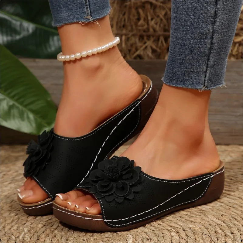 Poppy black slip-on wedge sandals with delicate floral upper detail and cushioned footbed for effortless style.
