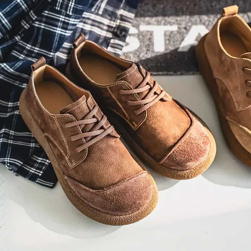 Brown suede lace-up walking shoes with a rounded toe, textured rubber sole, and contrast stitching on a white surface.