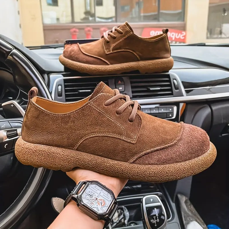 Men's brown suede lace-up walking shoes featuring a textured, cushioned sole and rounded toe design held inside a car.