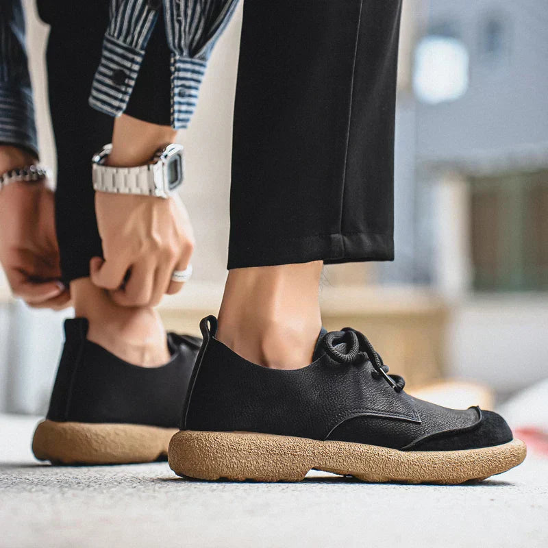 Men's black leather lace-up walking shoes with a textured tan cushioned sole, featuring a rounded toe and low-profile design.