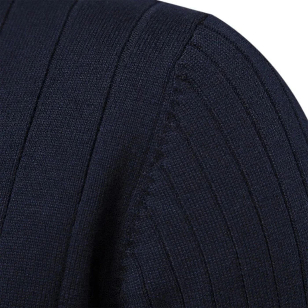 Close-up of a navy blue men's ribbed knit jumper showing the textured fabric and shoulder seam detail.