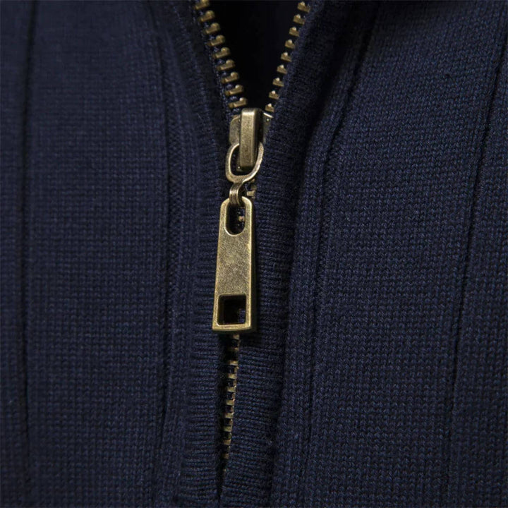 Close-up of a navy blue ribbed knit jumper featuring a metallic half-zip collar and textured fabric detail.