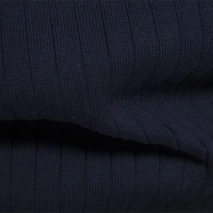 Close-up of a navy blue men's ribbed knit jumper, showcasing the soft, textured fabric and vertical knit pattern.