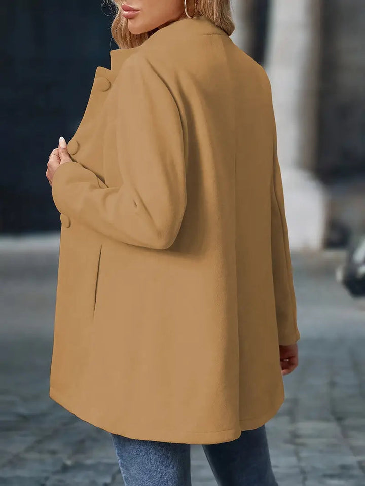 Camel-colored mid-length coat with a stand collar, covered button front, and tailored silhouette.
