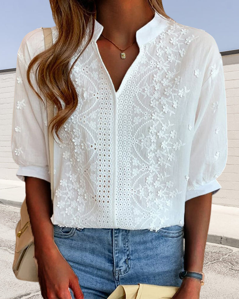 White V-neck blouse featuring intricate floral embroidery, eyelet detailing, and relaxed cuffed sleeves.