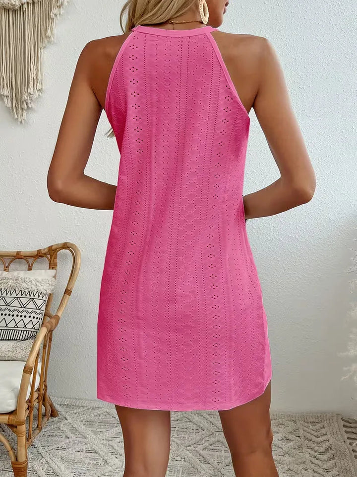 Back view of a bright pink eyelet halter mini dress with a relaxed A-line silhouette and delicate textured detailing.