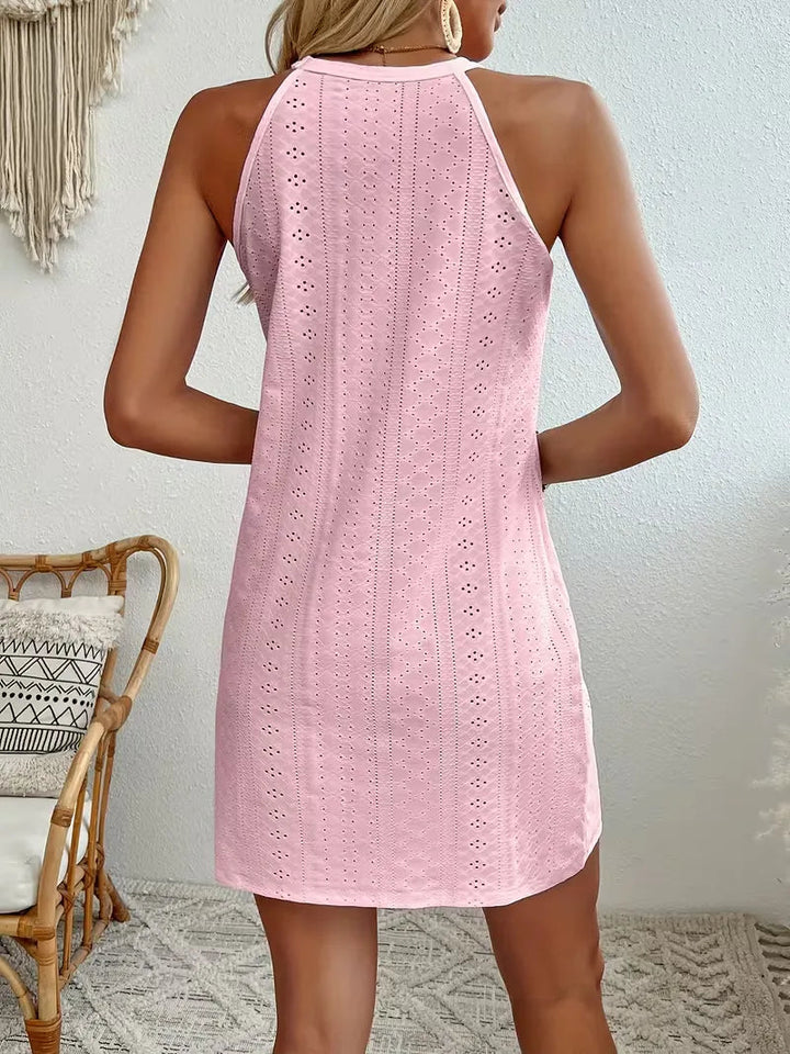 Back view of a light pink eyelet halter mini dress with a relaxed A-line fit and delicate lace detailing.