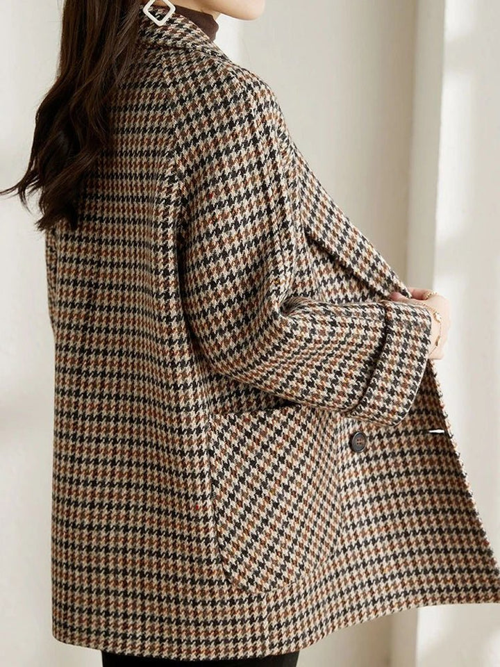 Women's brown and black houndstooth double-breasted blazer with a notched lapel and side pockets.