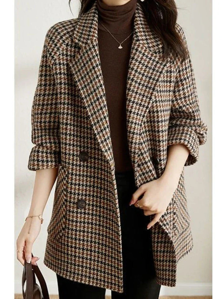 Women's brown and black houndstooth double-breasted blazer with notched lapels and side pockets worn over a brown turtleneck.