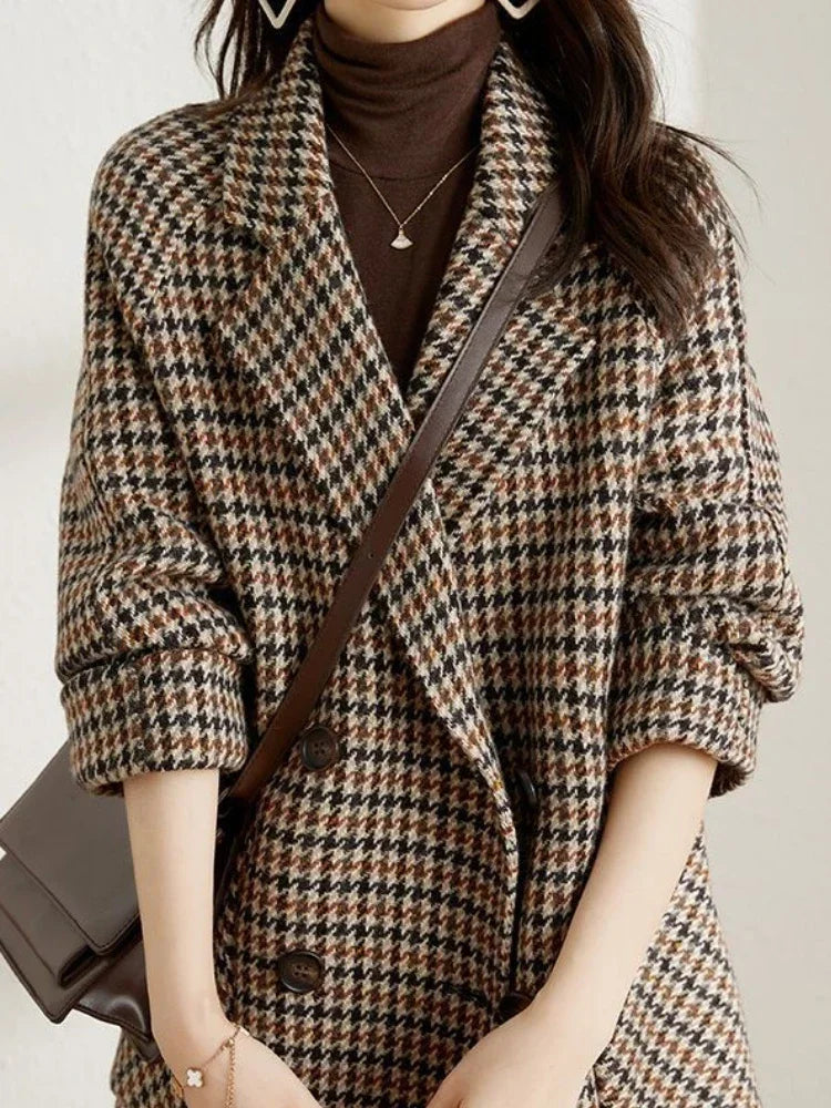 Women's brown and black houndstooth double-breasted blazer with a notched lapel and relaxed fit layered over a brown turtleneck.