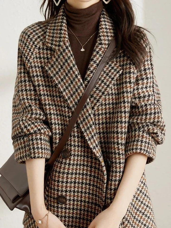 Women's brown and black houndstooth double-breasted blazer with a notched lapel and relaxed fit layered over a brown turtleneck.