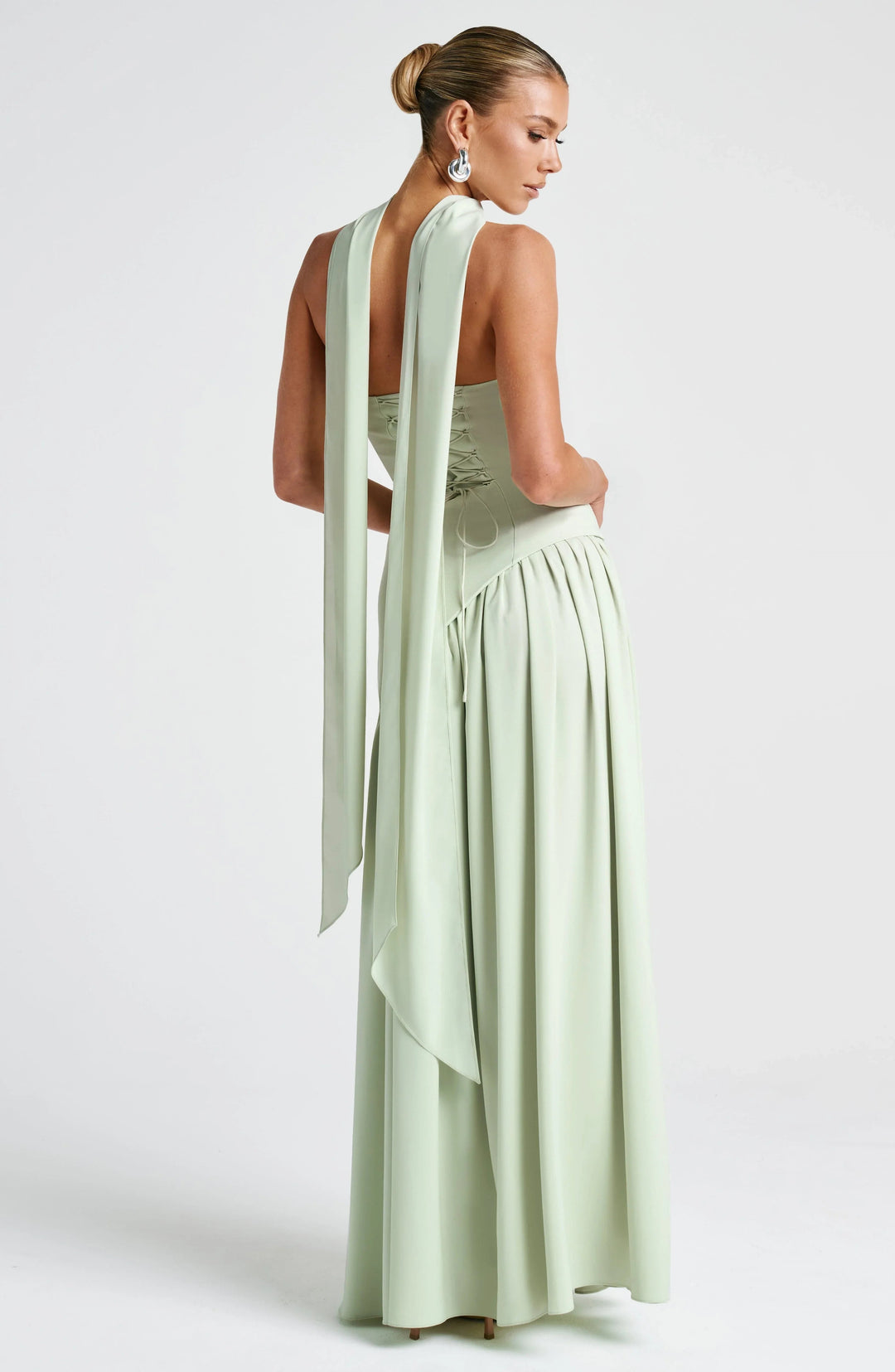 Sage green strapless corset maxi dress with lace-up back and elegant draped scarf panels.