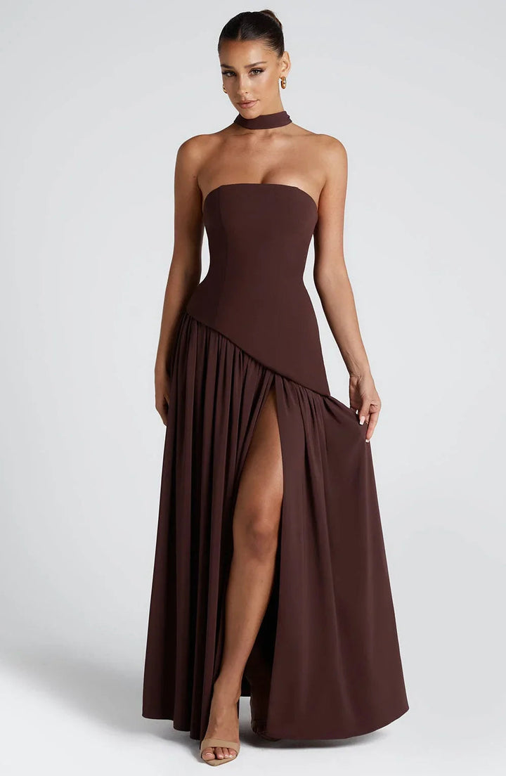 Model wearing a chocolate brown strapless corset maxi dress with a high leg slit and matching scarf detail.
