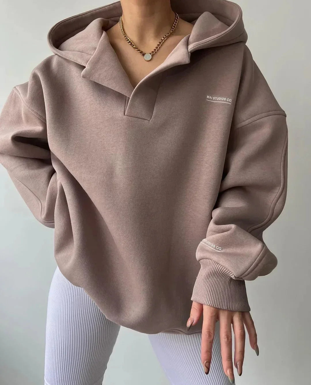 Taupe oversized V-neck hoodie with drop shoulders, ribbed cuffs, and subtle chest and sleeve branding.