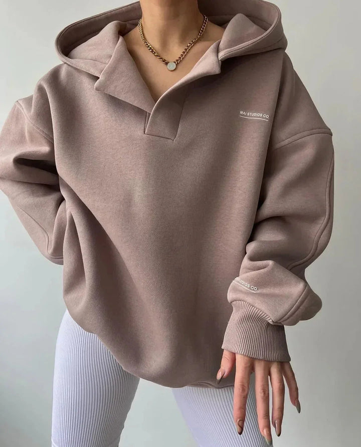 Taupe oversized V-neck hoodie with drop shoulders, ribbed cuffs, and subtle chest and sleeve branding.