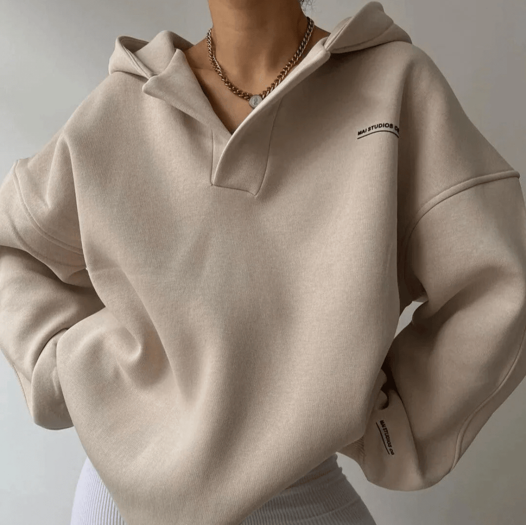 Beige oversized V-neck pullover hoodie with drop shoulders, ribbed cuffs, and subtle chest branding.