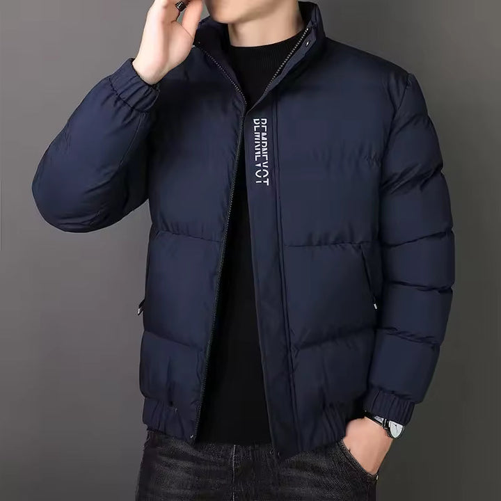 Navy blue men's puffer jacket with a stand collar, quilted insulated design, full-length zip, and ribbed cuffs.