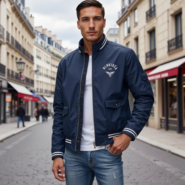 Navy blue zip-up bomber jacket with a stand collar, white striped trim, and chest logo, worn over a white t-shirt.