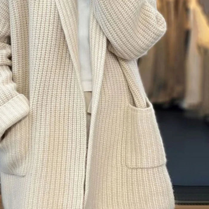 Cream-colored longline knit cardigan featuring a soft chunky texture, open front design, and convenient side pockets.