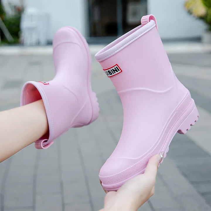 Light pink mid-calf waterproof rain boots with a grippy treaded sole and convenient back pull tab.