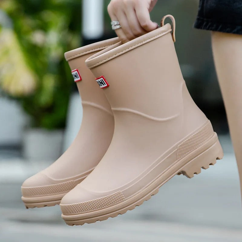 Beige mid-calf waterproof rain boots with a grippy treaded sole and a convenient back pull tab for easy wear.