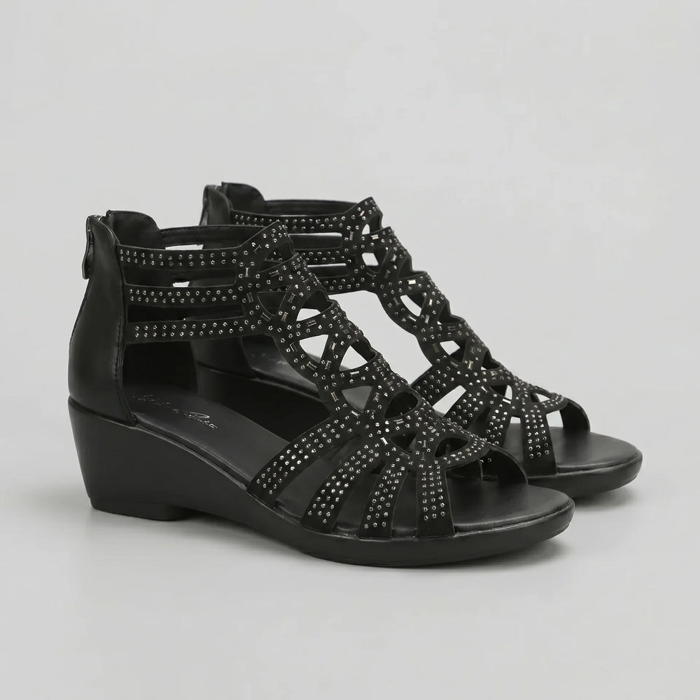 Black wedge sandals with embellishments on a light gray background