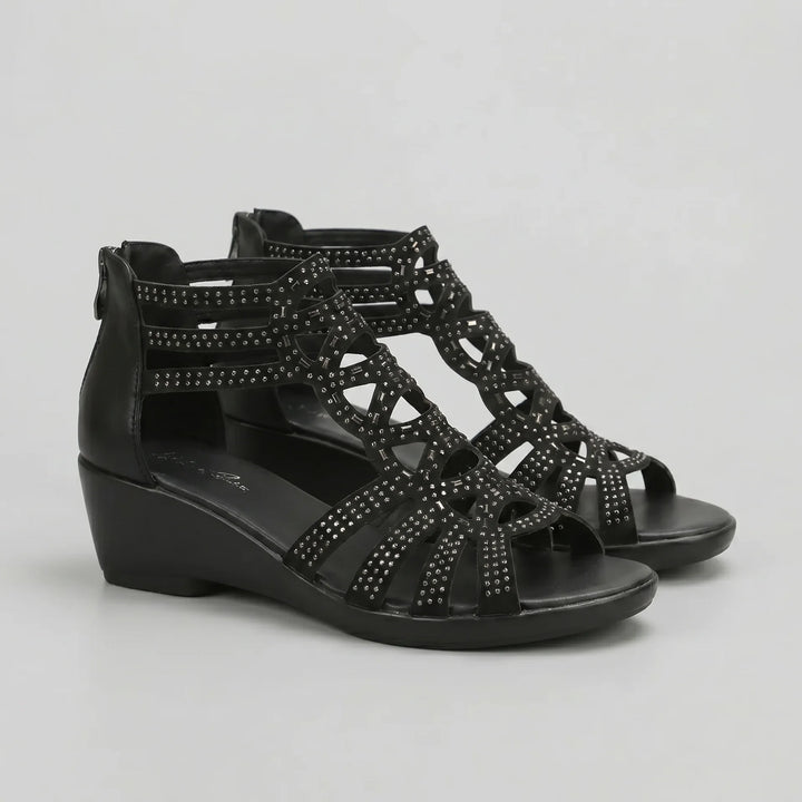 Black wedge sandals with embellishments on a light gray background