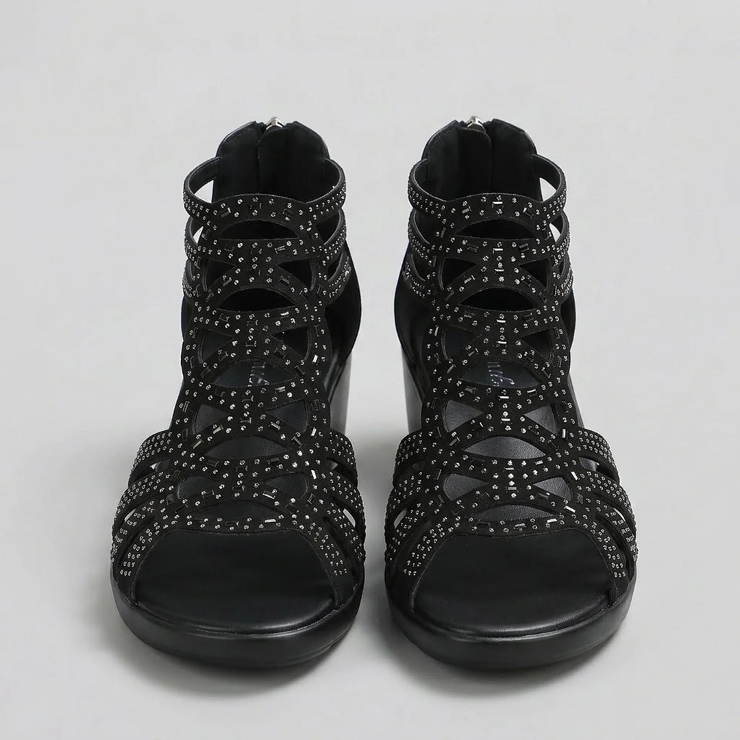 Black strappy sandals with embellishments on a light gray background