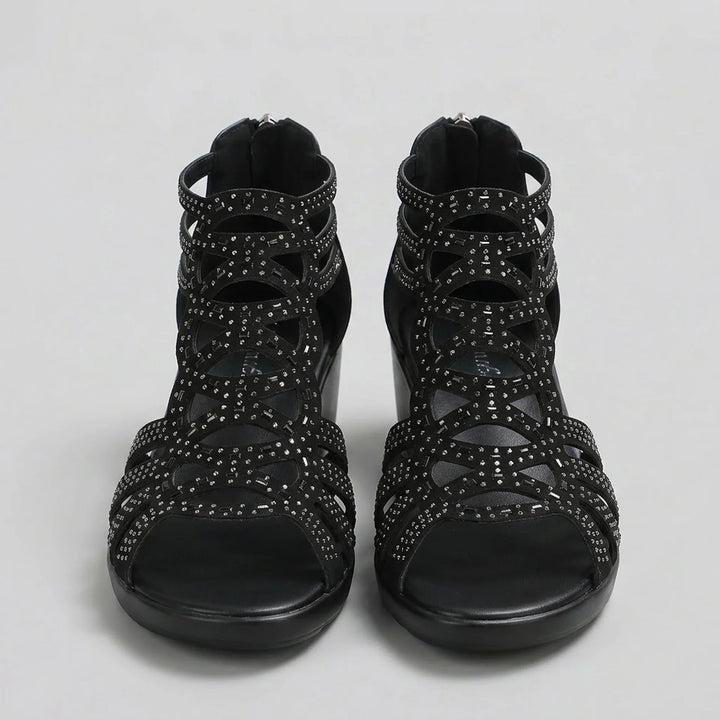 Black strappy sandals with embellishments on a light gray background