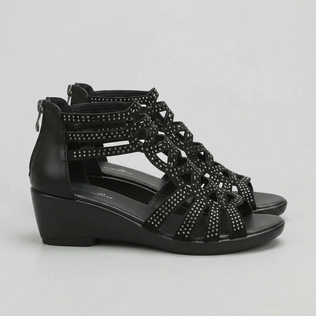 Black wedge sandal with studded details on a light gray background