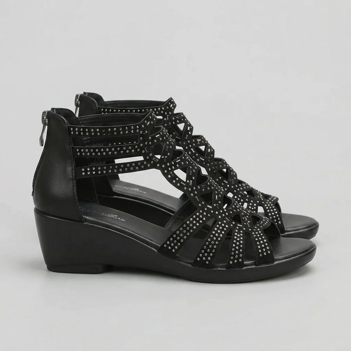 Black wedge sandal with studded details on a light gray background