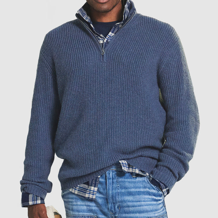 Blue ribbed knit quarter-zip jumper with a funnel collar, layered over a plaid shirt and jeans for a smart, warm look.