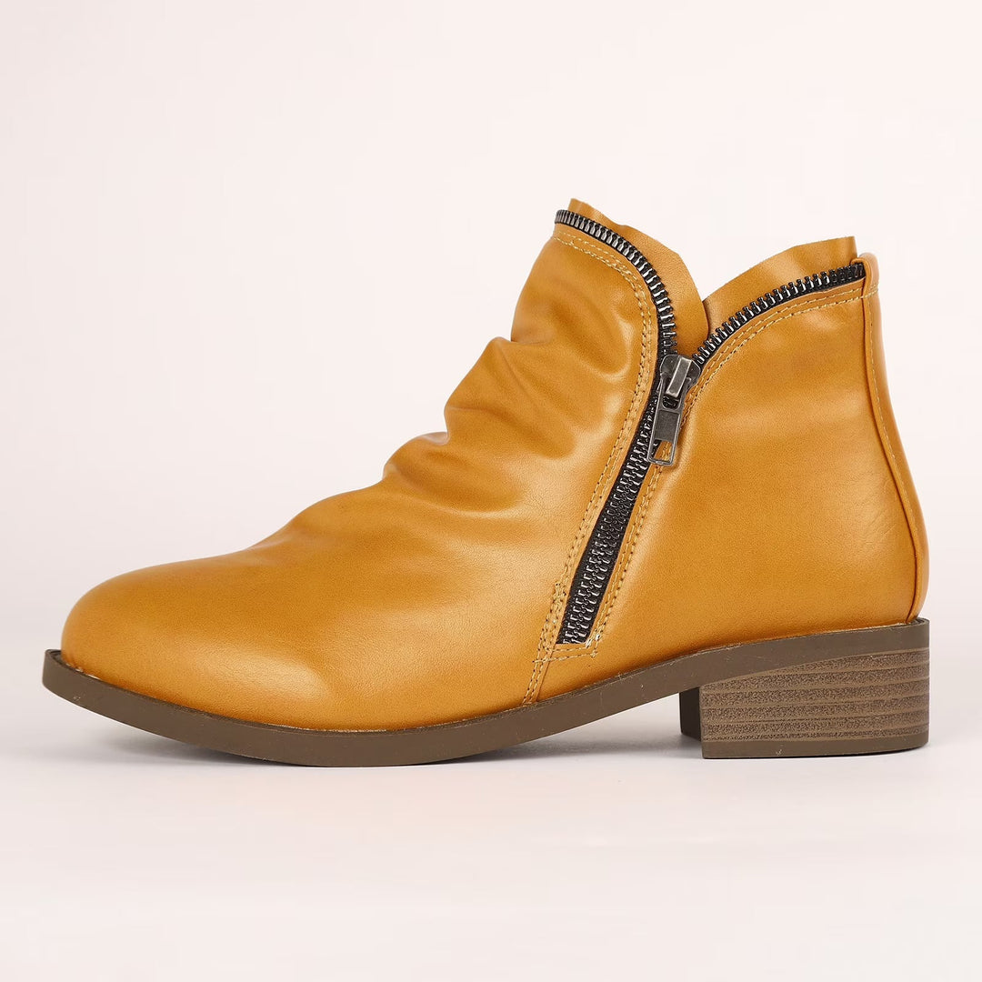 Mustard yellow Tilly ankle boots featuring a soft ruched upper, side zip closure, and a comfortable low block heel.