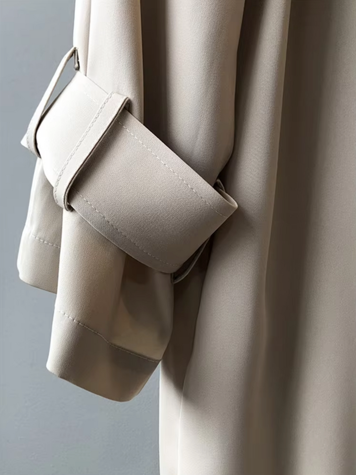 Beige waterproof trench coat sleeve featuring a refined buttoned tab detail and smooth, high-quality tailored fabric.