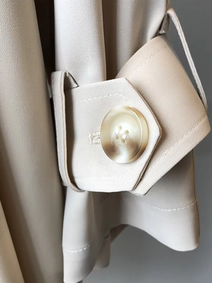 Beige waterproof trench coat sleeve featuring a refined buttoned tab detail and premium tailored stitching.