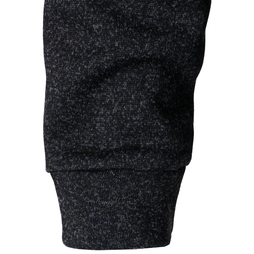 Close-up of a black marled knit sweater sleeve with a ribbed cuff, showcasing the soft, textured fabric detail.